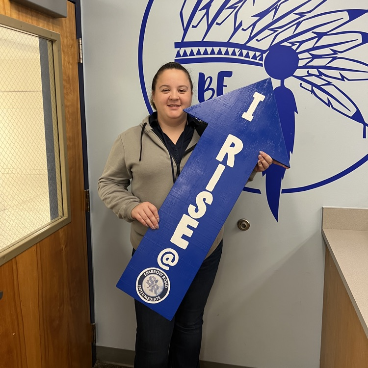 Mrs. Jarvis holding the I RISE arrow in the main lobby.