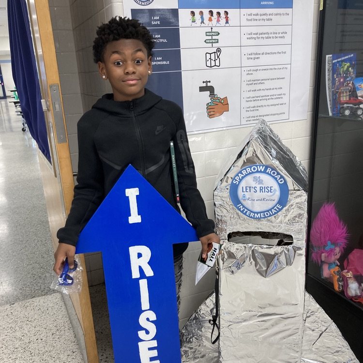 A student with the I RISE arrow in the main lobby.