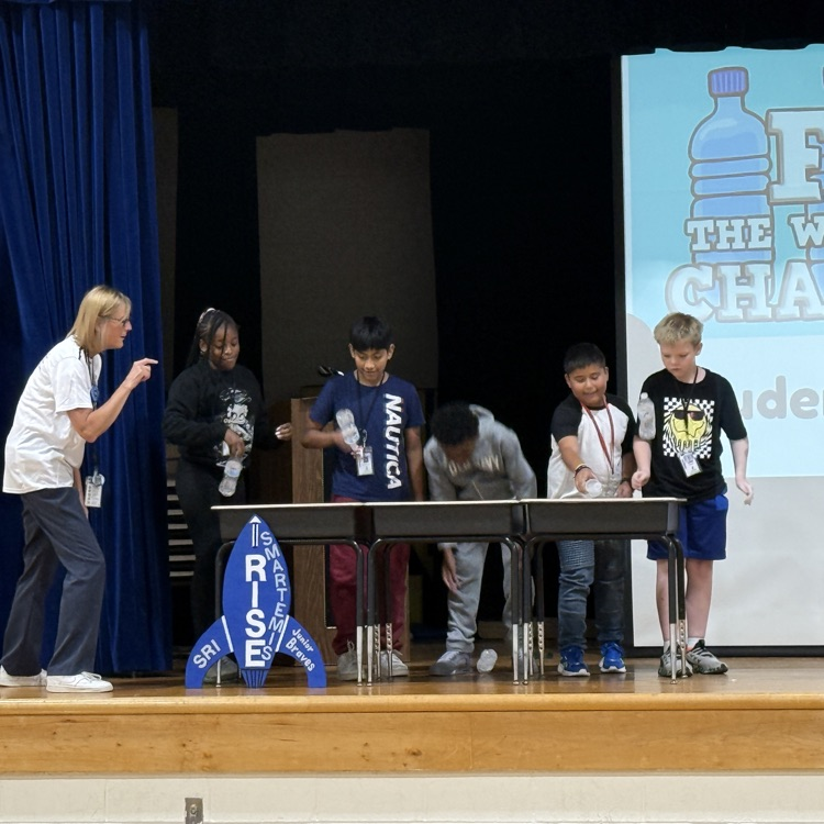 5th Grade students flipping water bottles on stage. 