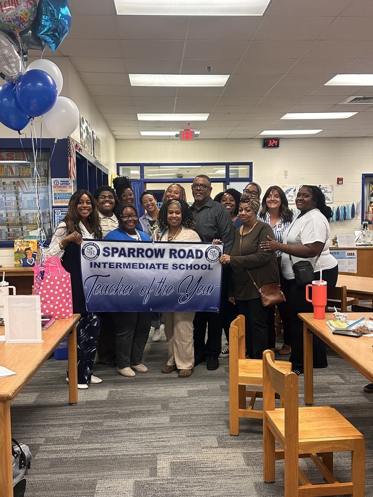 SRI Teacher of the Year sign being held by Mrs. Daniels and friends and family.