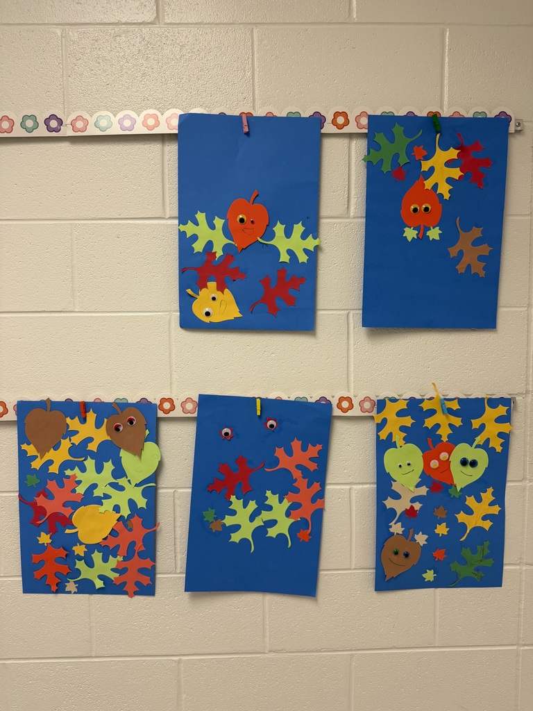 student Leaf Man art hanging in hallway mentioning leaves decorated to have faces