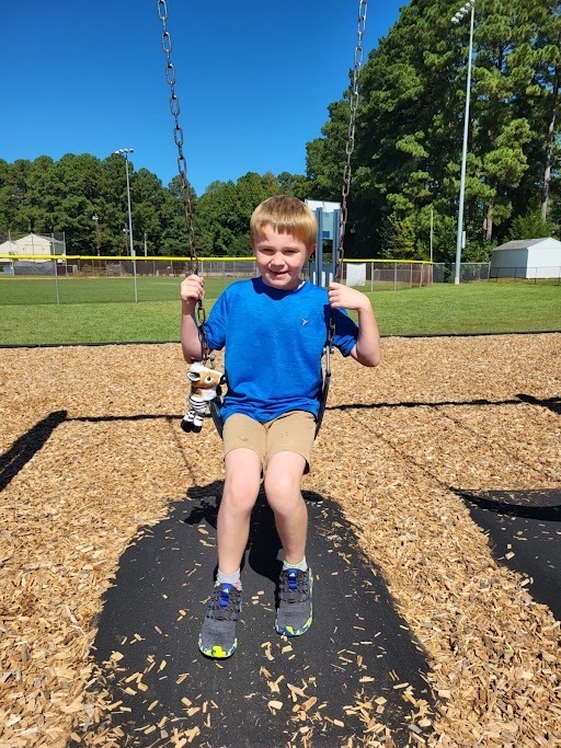 Student on swing with stuffed animal