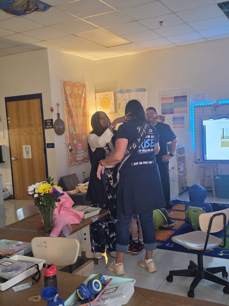 Mrs. Alexander adjusting Mrs. Yohe's hair after draping her with her teacher of the year sash