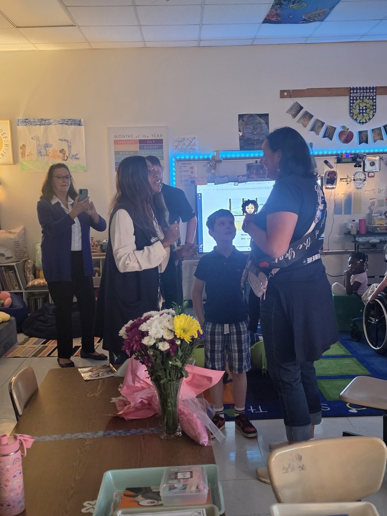 Principal Alexander offering congratulations to Mrs. Yohe as her family looks on