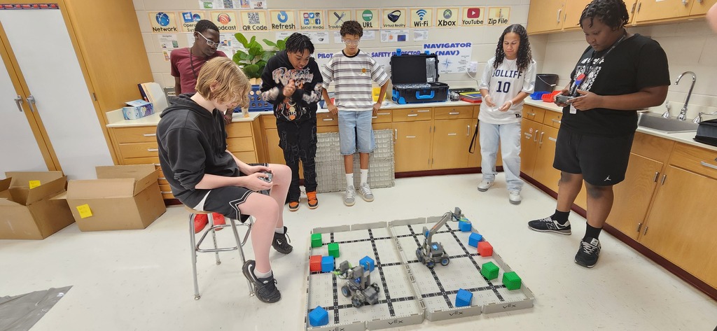 Student's directing robots to pick up foam blocks and move them to specific locations