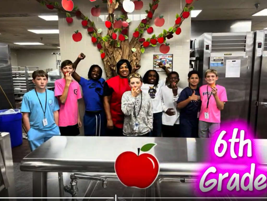 A JMS cafeteria staff member and 8 6th grade students participating in the Crunch heard around the Commonwealth event by biting into apples