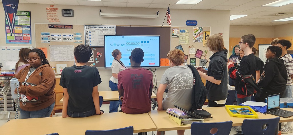 group of 8th students in technology elective, reviewing the results of their robotics race