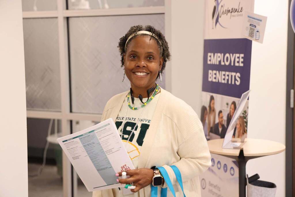 Employee smiling at the Benefits Open Enrollment Fair with resources to help them.