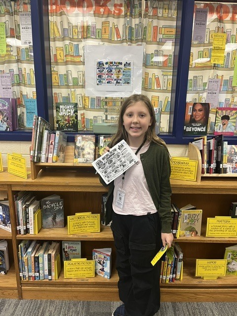 Student holding up their completed Genre Bingo Challenge Card.