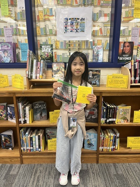 Student holding up their completed Genre Bingo Challenge Card.