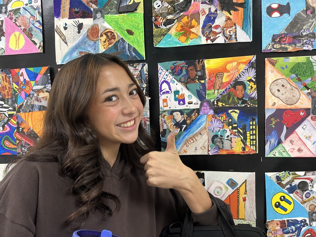 student giving the thumbs up with her artwork