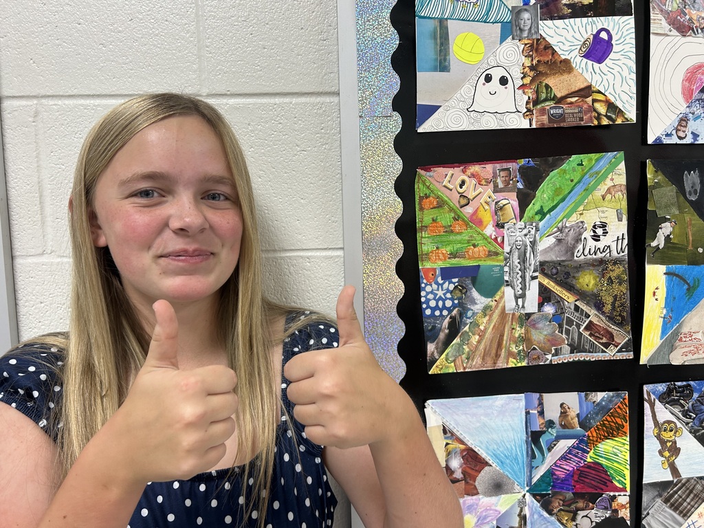 student giving the thumbs up with her artwork