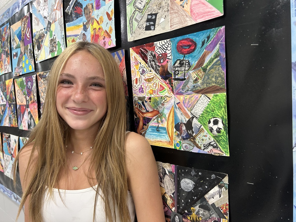 student proudly posing with her artwork