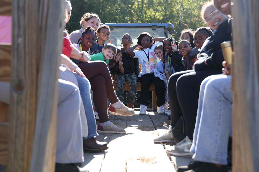students and teachers smile happily from the back of a hayride