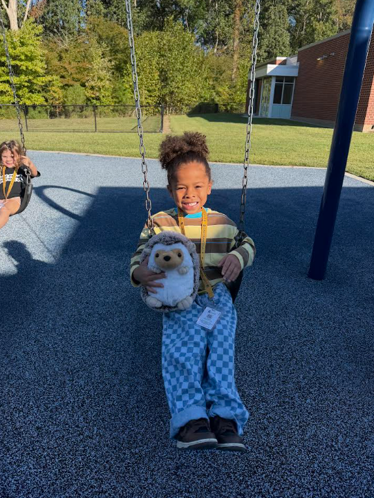 Kindergarten student swinging with Hedgie the Hedgehog