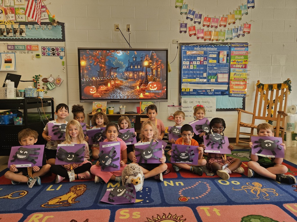 Mrs. Kiskinis' students posing proudly with their spider crafts, along with Hedgie the Hedgehog stuffed animal.