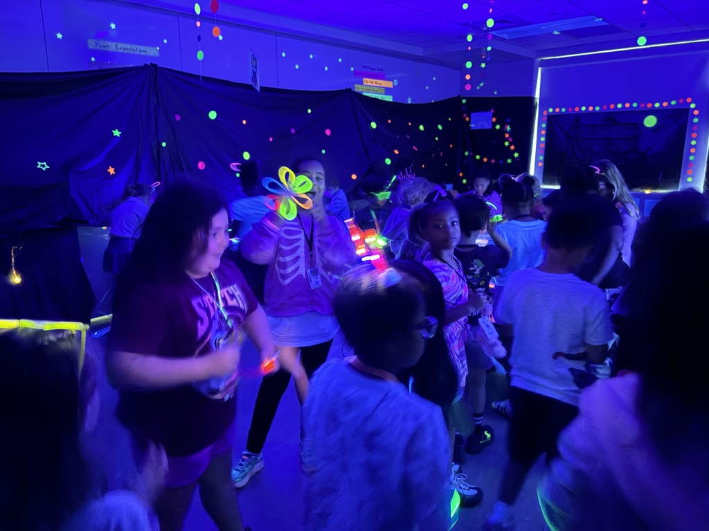 Kids playing with glow sticks under a blacklight.