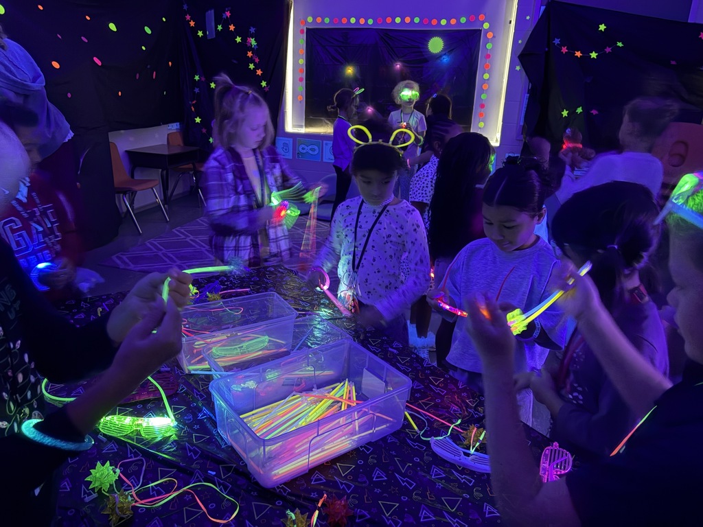 Kids playing with glow sticks under a blacklight.