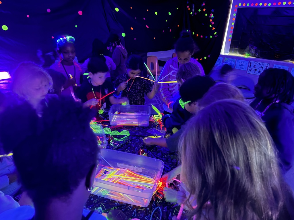 Kids playing with glow sticks under a blacklight.