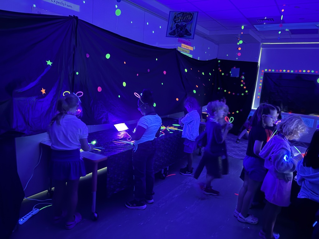 Kids playing with glow sticks under a blacklight.
