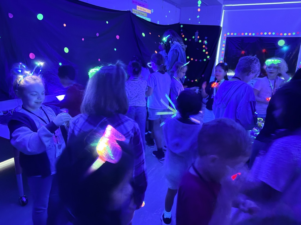 Kids playing with glow sticks under a blacklight.