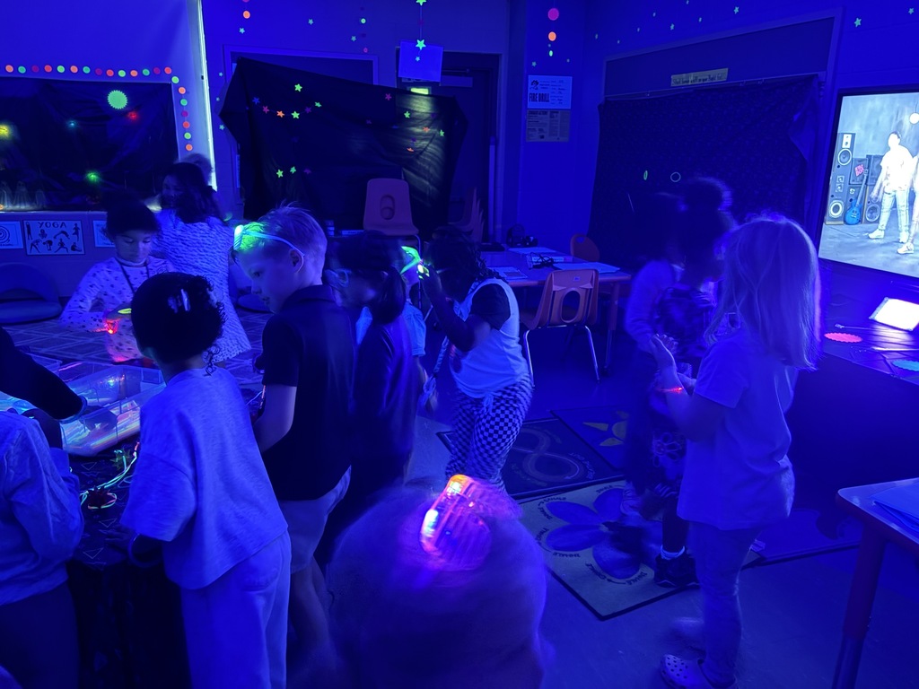 Kids playing with glow sticks under a blacklight.
