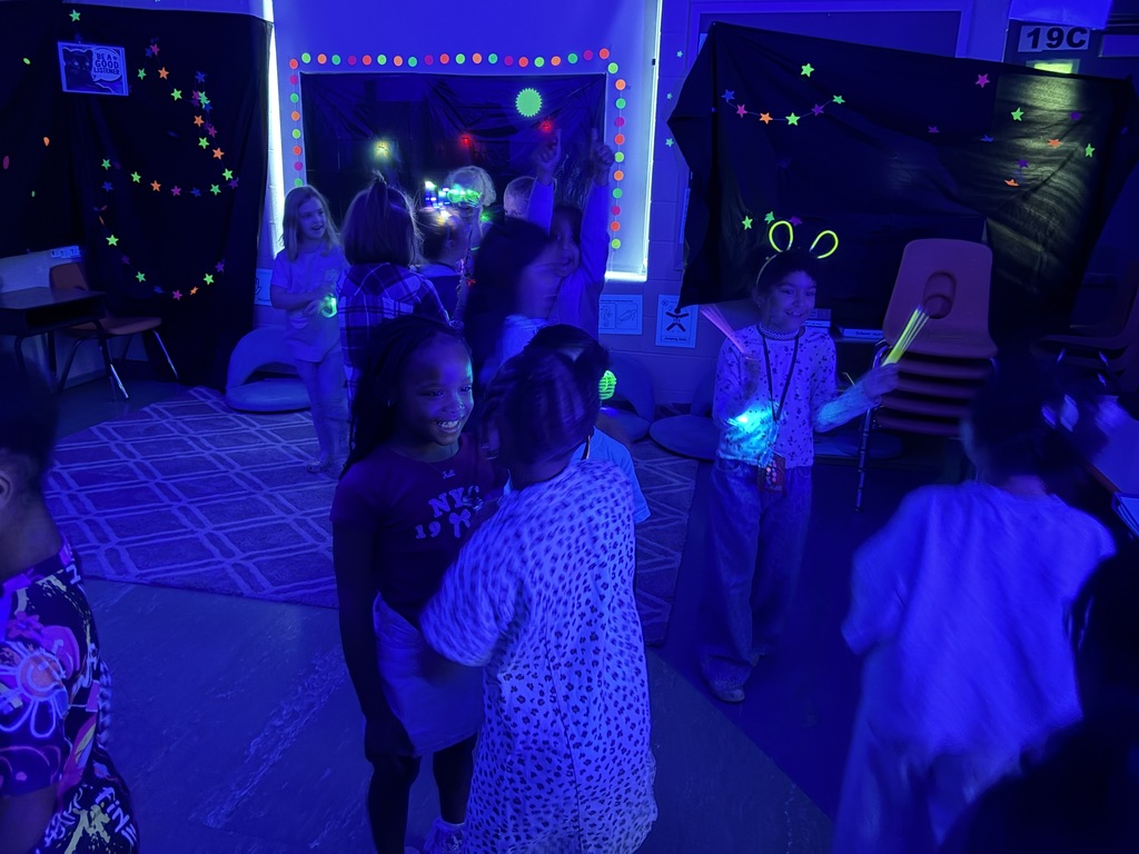 Kids playing with glow sticks under a blacklight.