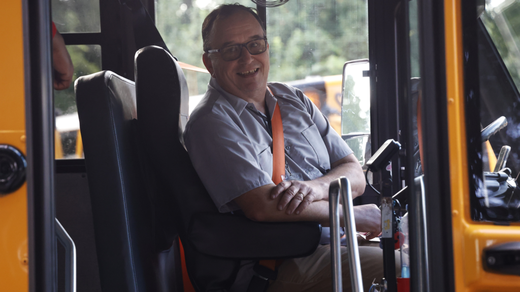 bus driver smiles from bus on first day