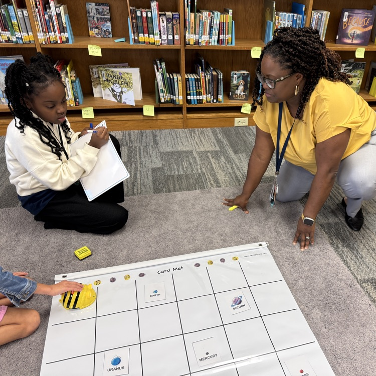 Mrs. Young and a student work to code the bee bot.