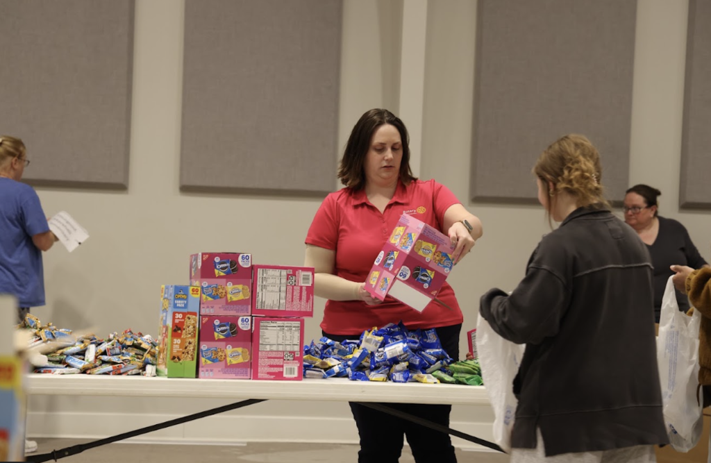 Two people organize can goods for the Blessings in a Backpack program