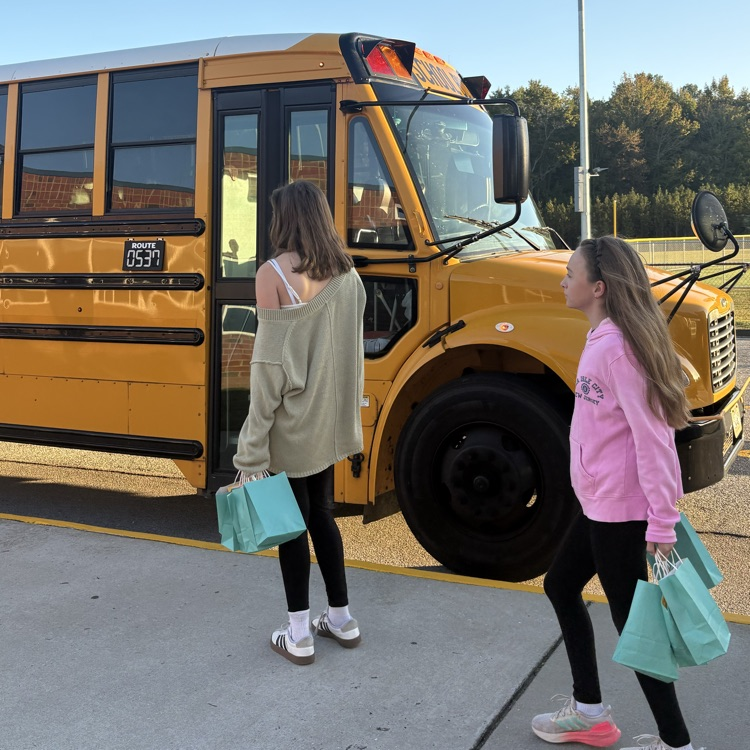 student delivering bag to bus driver
