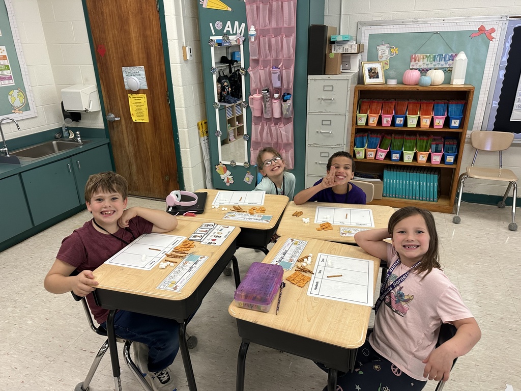 Enthusiastic 2nd grade students at Treakle Elementary smiling as they build place value math models using Cheez-Its, pretzel sticks, and mini marshmallows.