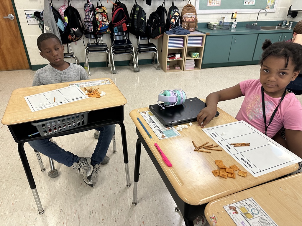 Enthusiastic 2nd grade students at Treakle Elementary smiling as they build place value math models using Cheez-Its, pretzel sticks, and mini marshmallows.