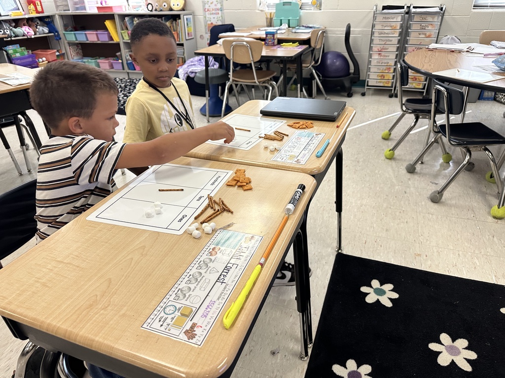 Enthusiastic 2nd grade students at Treakle Elementary smiling as they build place value math models using Cheez-Its, pretzel sticks, and mini marshmallows.