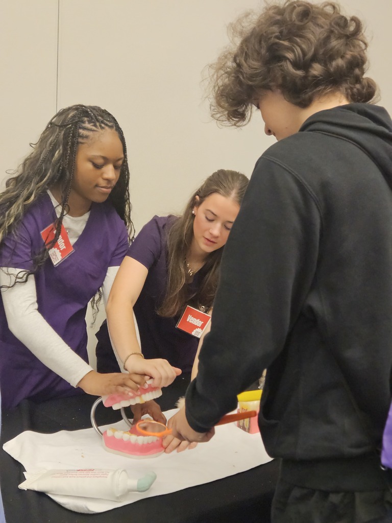 Dental students at world of works showing their program to 8th graders.