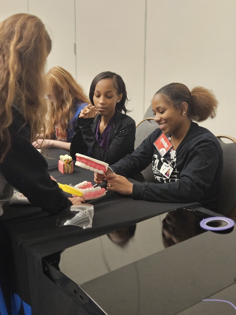 Dental students at world of works showing their program to 8th graders.