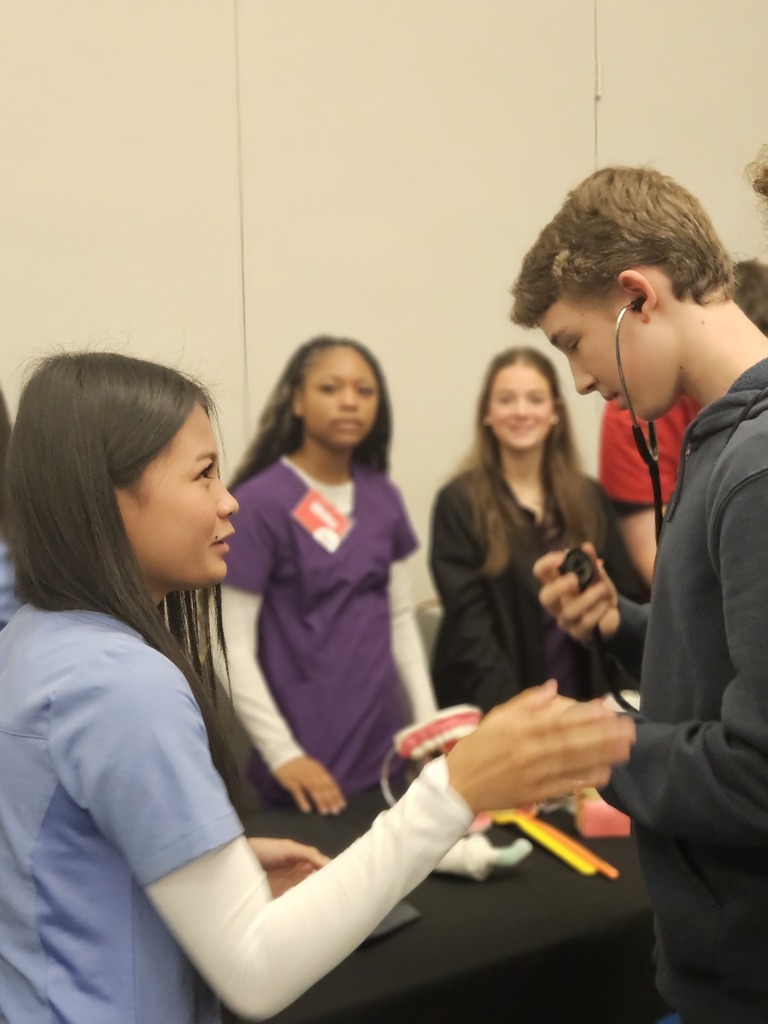 Patient Care Tech students at world of works showing their program to 8th graders.