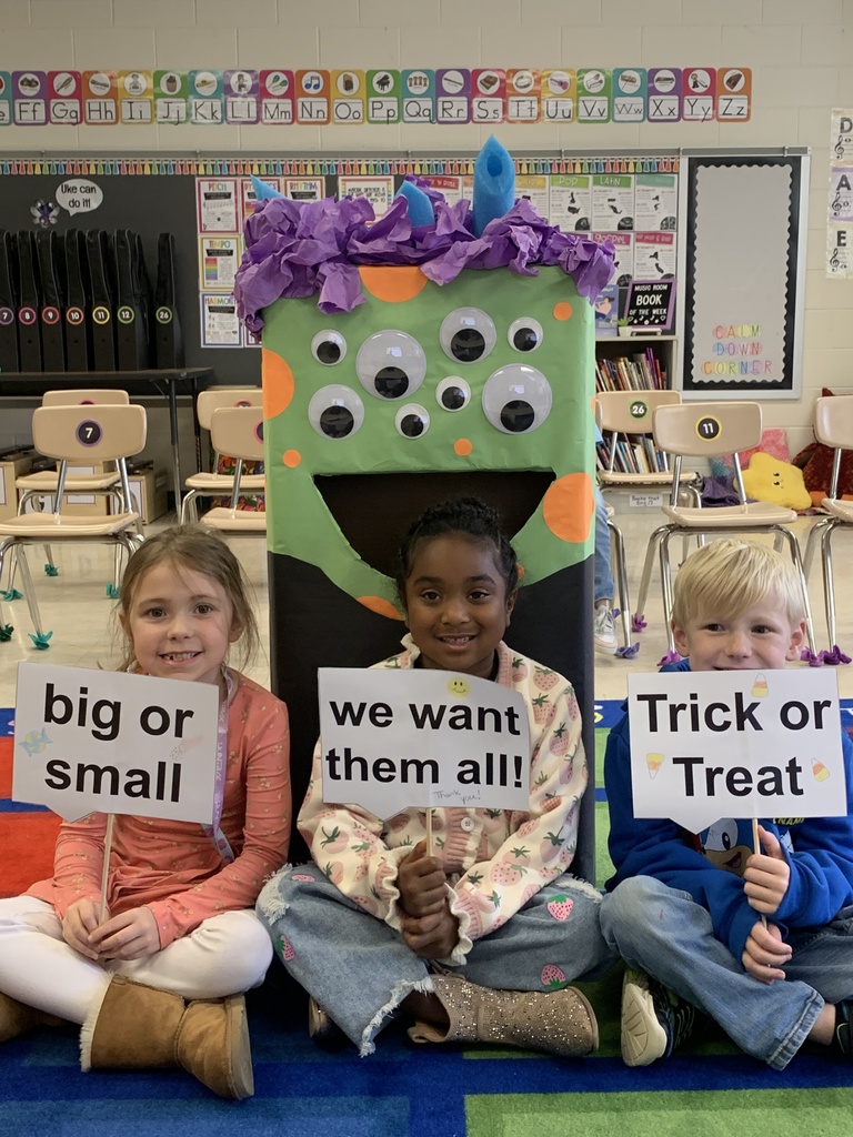 Students posing with Victor the candy  monster, sign says "big or small, we want them all! Trick or Treat."
