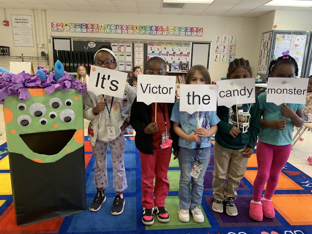 Students posing with Victor the candy  monster, sign says "It's Victor the candy monster"