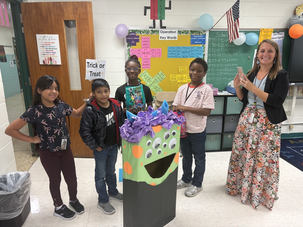 Students posing with Victor the candy  monster, sign says "Trick or Treat."