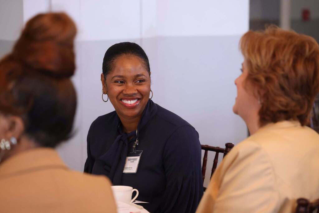Community member smiling at a table at the Superintendent's Community Engagement Council.