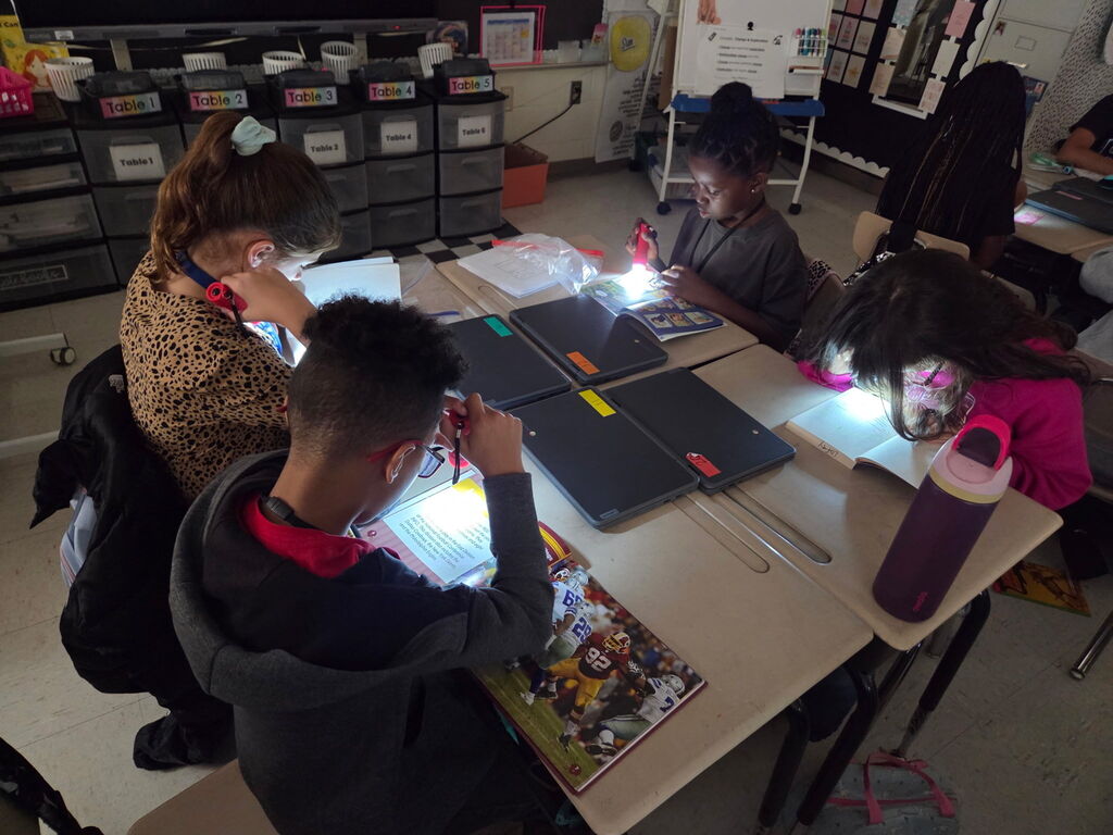 students reading with flashlights in the classroom