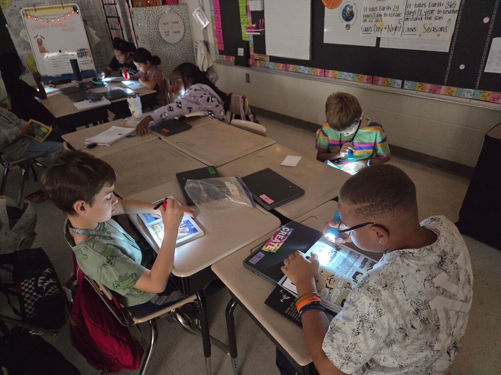 students reading with flashlights in the classroom