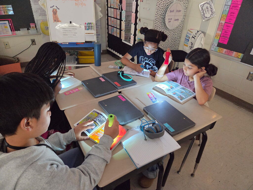 students reading with flashlights in the classroom
