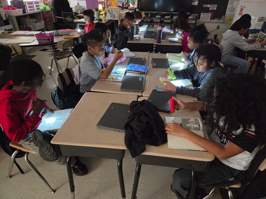 students reading with flashlights in the classroom