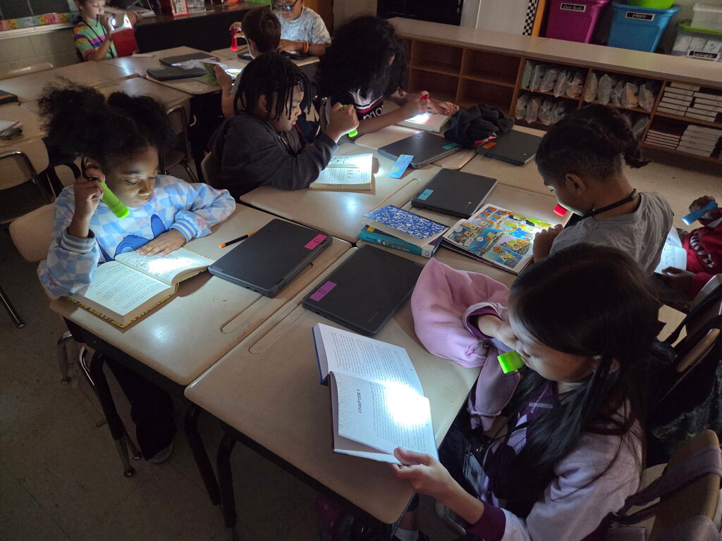 students reading with flashlights in the classroom