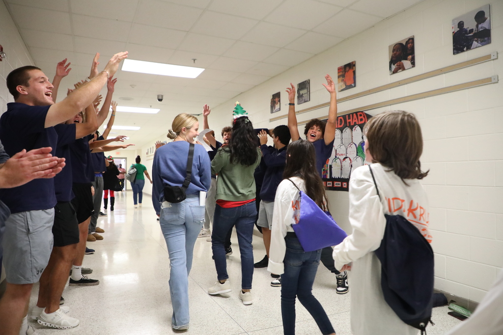 Students walking into a school surrounded by college students cheering them on.