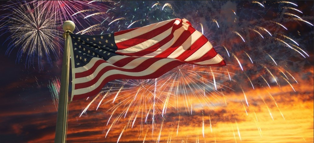 American flag at night surrounded by fireworks
