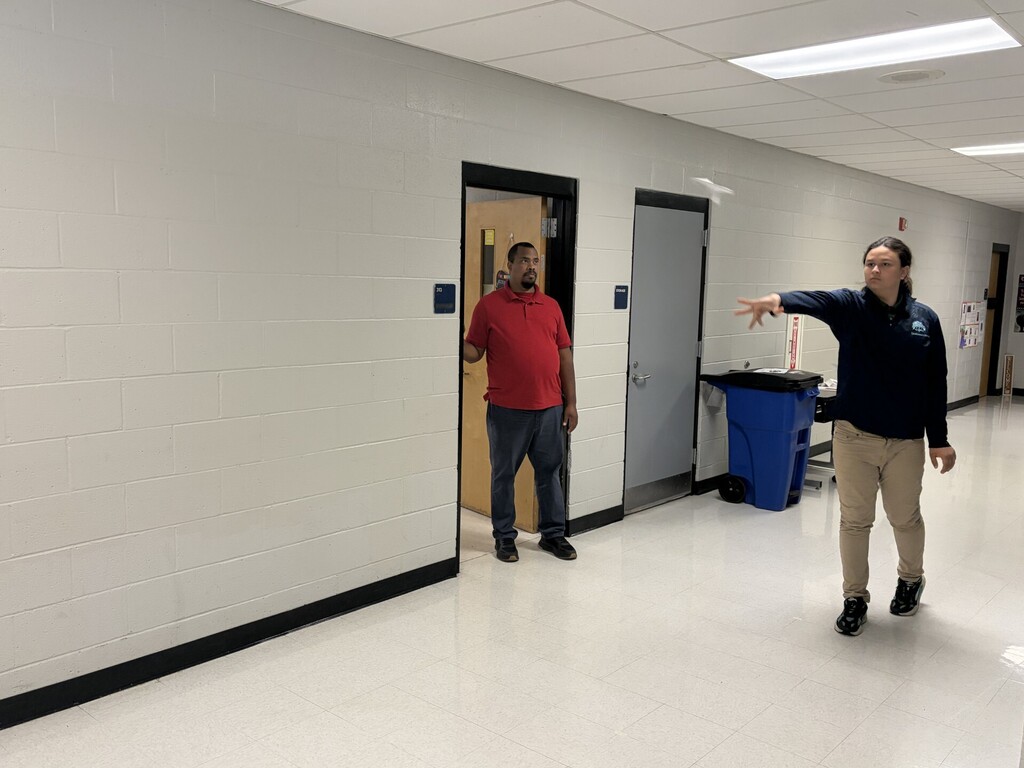 A student launching his airplane down the hall. 