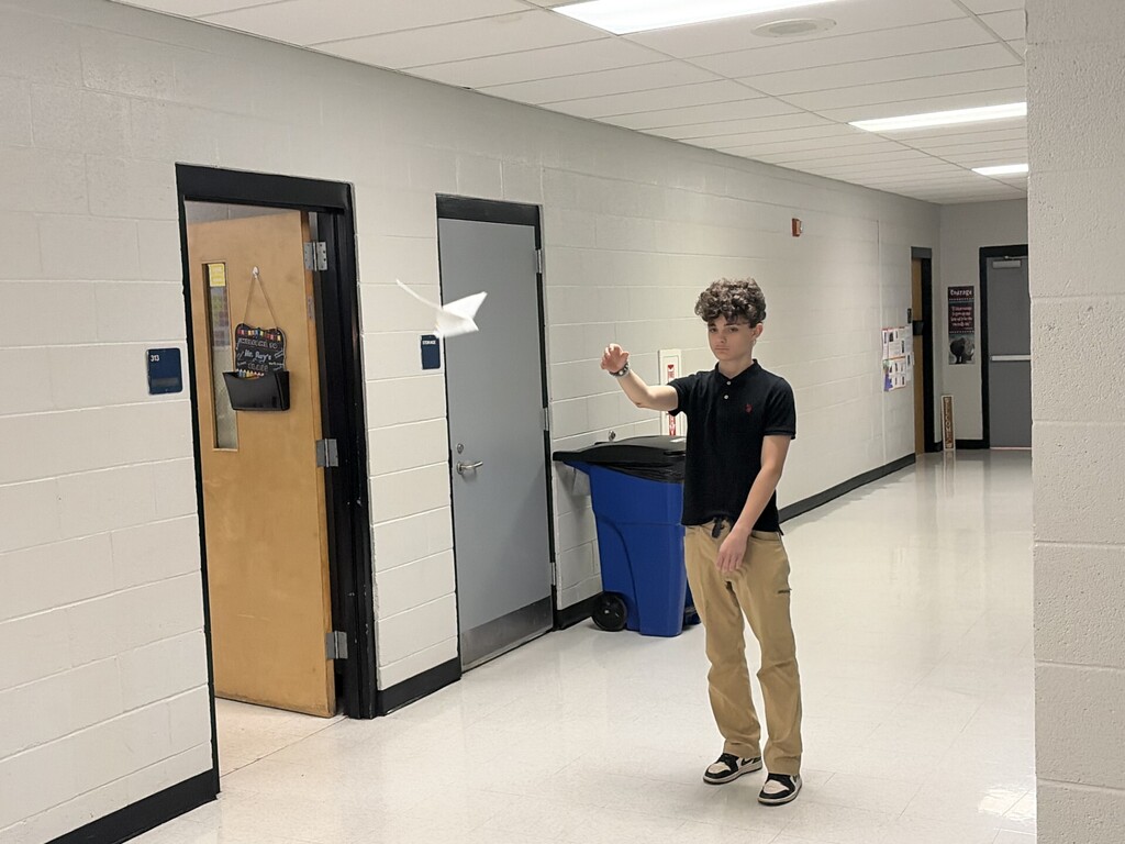 A student watching his airplane fly right towards the camera. 